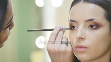 güzel genç esmer kadına uygulanan göz bölgesi kozmetik fırça ile telafi portresi yukarıya kapatmak