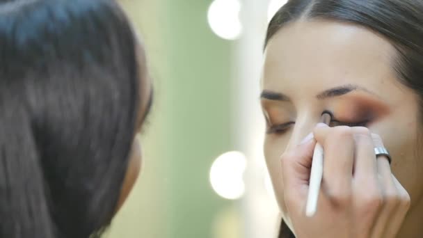 Primer plano retrato de hermosa joven morena aplicación de zona ocular maquillaje con cepillo cosmético — Vídeos de Stock