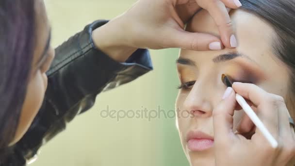 Primer plano retrato de hermosa joven morena aplicación de zona ocular maquillaje con cepillo cosmético — Vídeos de Stock