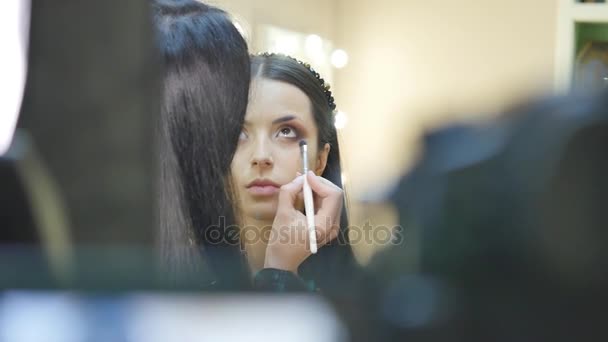 Close-up van portret van mooie jonge brunette vrouw toepassen oog-zone make-up met cosmetische borstel — Stockvideo