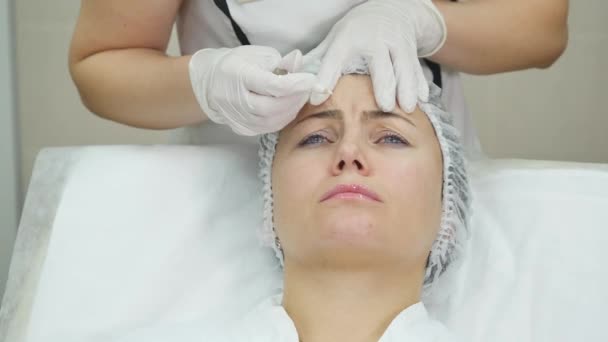 Jonge mooie vrouw krijgen van cosmetische injectie in het gezicht als een deel van de behandeling van de kliniek. — Stockvideo