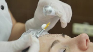 Güzellik uzmanı kadın yüzü krem maske uygulayarak el kapatın. Fırça tutuyor. Güzel genç kadın gevşeme ile yatıyor