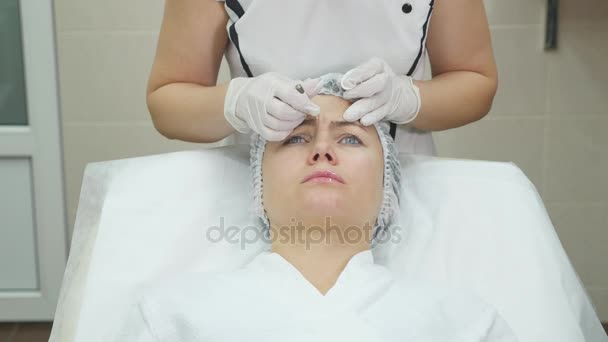 의사는 얼굴 성형 수술을 병원에서 환자 얼굴에 표시와 함께 라인을 그립니다. — 비디오