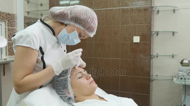 Beautiful young woman is getting botox injection in her cheek. — Stock Video