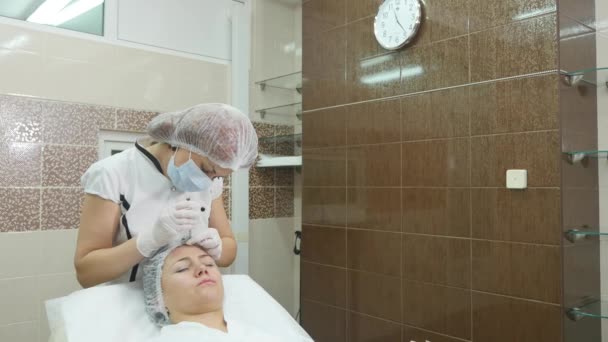 Όμορφη νεαρή γυναίκα παίρνει ένεση botox στο μάγουλό της. — Αρχείο Βίντεο