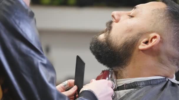 Primer plano guapo joven barbudo conseguir barba aseo en moderna barbería . — Vídeo de stock