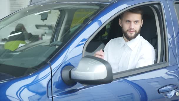 Jeune homme assis dans la voiture tenant des clés de voiture — Video