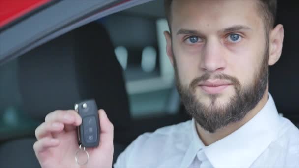 Молодий чоловік сидить у машині тримає ключі від машини — стокове відео