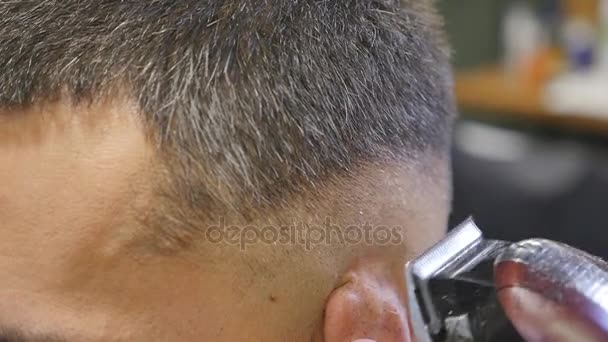 Чтобы волосы выглядели волшебно. Молодой бородатый мужчина стрижется бритвой от парикмахера сидя в кресле в парикмахерской — стоковое видео