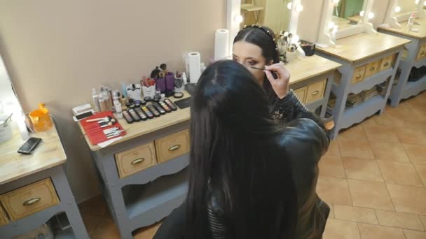 Νεαρή όμορφη Ασιάτισσα που βάζει μακιγιάζ από μακιγιέρ — Αρχείο Βίντεο
