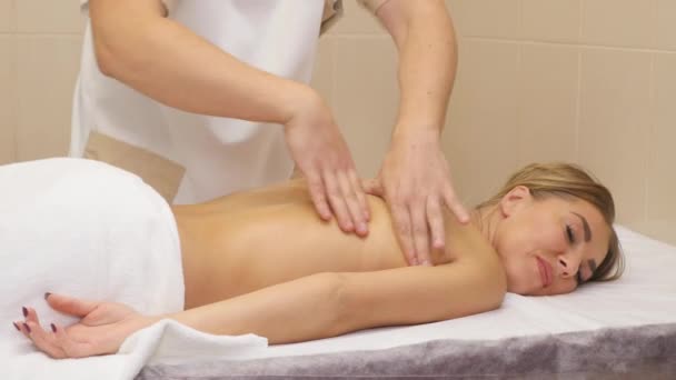 Schöne junge Frau bekommt Rückenmassage im Wellnessbereich — Stockvideo