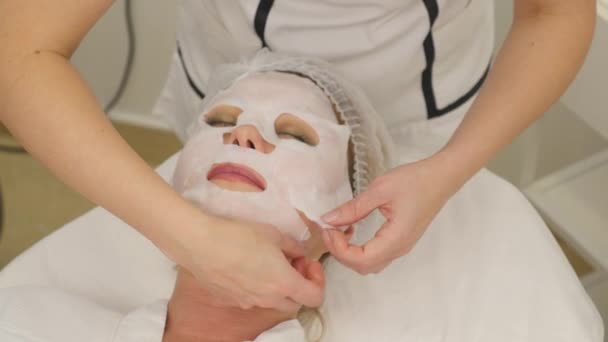 Фотография красивого косметолога, делающего процедуру рф-лифтинга для женщины, лежащей в салоне красоты — стоковое видео