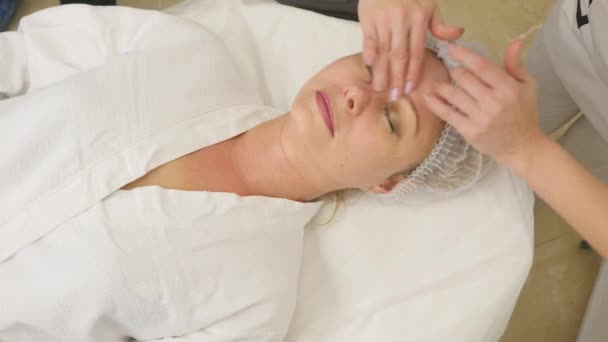 Esthéticienne applique un masque facial sur la peau des filles — Video