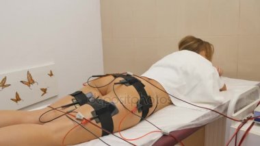 Güzel bir kadın güzellik salonunda elektrostimülasyon tedavisi görüyor.