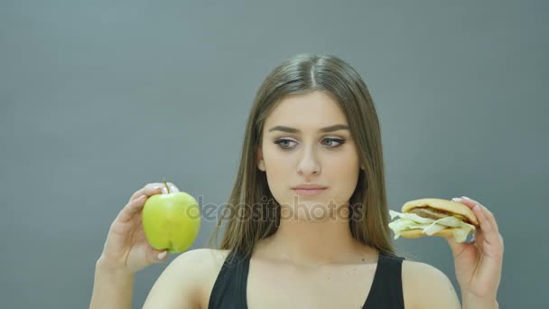 Scelta difficile: mela o hamburger, ragazza agitata ha deciso di andare a dieta — Video Stock