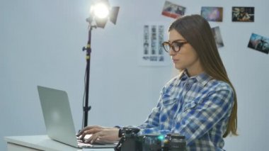 Kadın fotoğrafçı onu profesyonel fotoğraf stüdyosu bir dizüstü bilgisayar, kamera ve aydınlatma donanımları ile çalışma