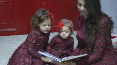 Şirin kızları bir kitap okuma neşeli Noel ve mutlu tatiller çok genç anne. Flaş ışığı ile Photoshoot