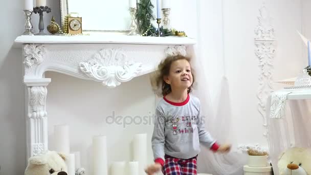 Mädchen im Schlafanzug springt auf dem Bett. das Konzept von Weihnachten. Fotoshooting mit Blitzlicht — Stockvideo