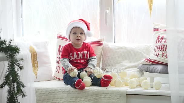 Hermoso bebé celebra la Navidad. Vacaciones de Año Nuevo. Niño en un disfraz de Navidad con regalo. Santa Kid. — Vídeos de Stock