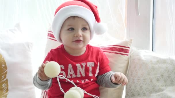 사랑 스러운 작은 소년 크리스마스 장식과 빛나는 갈 랜드 집에서 놀고. 플래시 빛 사진 — 비디오