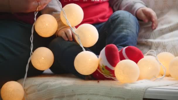 Adorabile bambino che gioca con decorazioni natalizie e ghirlanda luminosa a casa. Photoshoot con luce flash — Video Stock