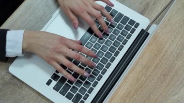 Dizüstü bilgisayarda yazı yazan kadının hava görüntüsü. Tahta masaya yerleştirilmiş.