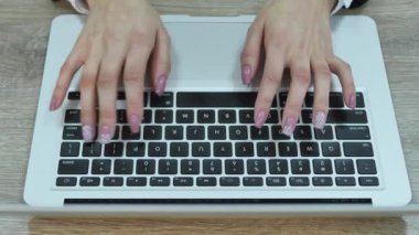 Dizüstü bilgisayarda yazı yazan kadının hava görüntüsü. Tahta masaya yerleştirilmiş.