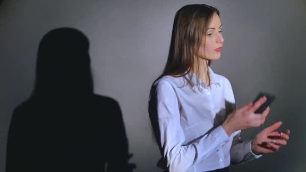 Joven mujer elegante hablando en el teléfono móvil sobre fondo negro con sombra — Vídeos de Stock