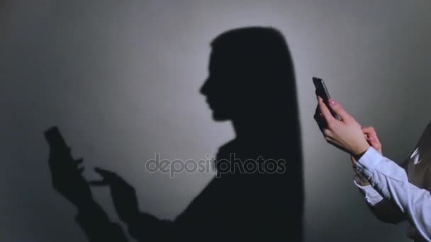 Ung elegant kvinna som pratar i mobiltelefon mot svart bakgrund med skugga — Stockvideo