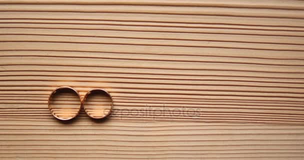 Złote obrączki ślubne na podłoże drewniane — Wideo stockowe