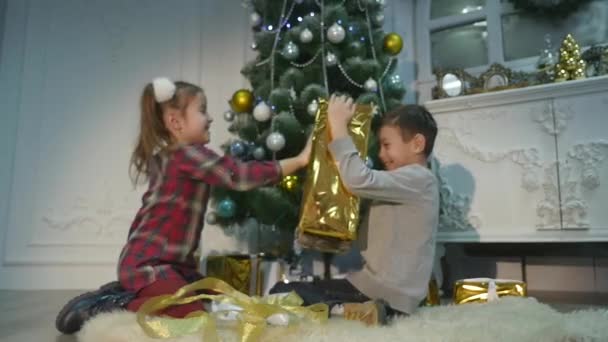 Дети распаковывают сюрприз на Рождество. Концепция праздников — стоковое видео