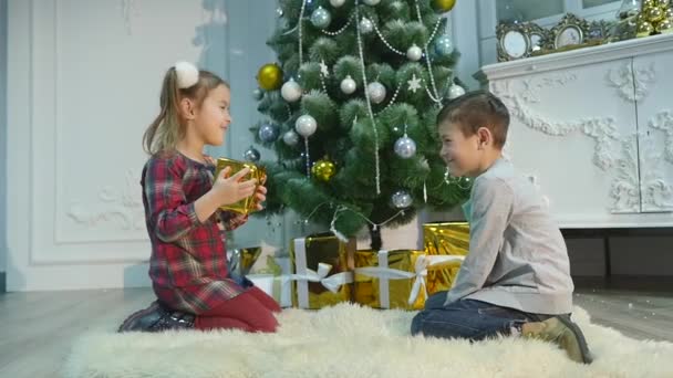 Irmãozinho e irmãzinha desempacotar presentes. O conceito de Natal e Ano Novo — Vídeo de Stock