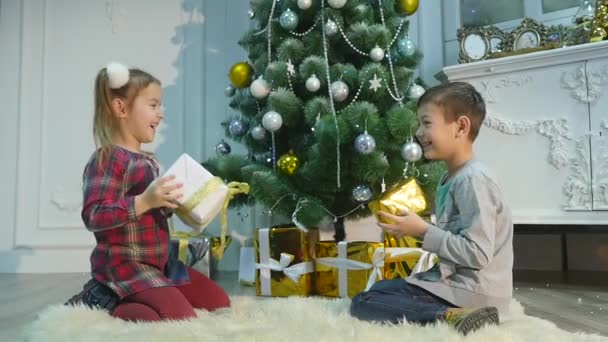 Fratellino e sorella disfanno i regali. Il concetto di Natale e Capodanno — Video Stock