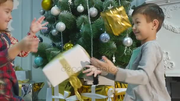 Weihnachtsgeschenke, die Kinder aufeinander werfen — Stockvideo