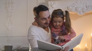 Genç kızı şömine, oturma ve Noel arifesinde hikaye baba