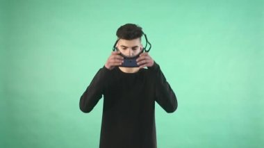 Yeşil arka plana karşı sanal bir gözlük kullanan genç adam