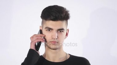 Cep telefonunuza konuşan şaşkın şaşkın genç adam. Adam portre düşünme ve telefon konuşma