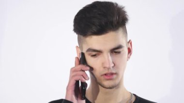 Cep telefonunuza konuşan şaşkın şaşkın genç adam. Adam portre düşünme ve telefon konuşma