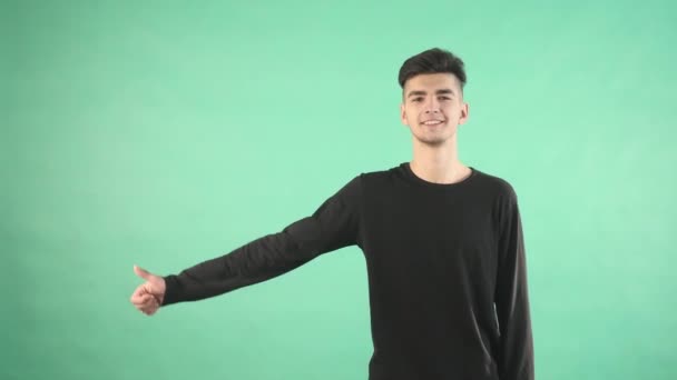 Giovane uomo sorridente con i pollici in su isolato su uno sfondo verde — Video Stock