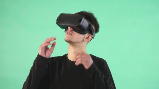 Young man using a virtual glasses against green background — Stock Video