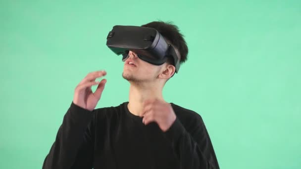 Mladý muž používající virtuální brýle proti zeleným pozadím — Stock video