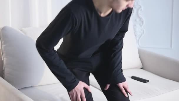 Junger Mann sitzt mit Fernbedienung auf der Couch — Stockvideo