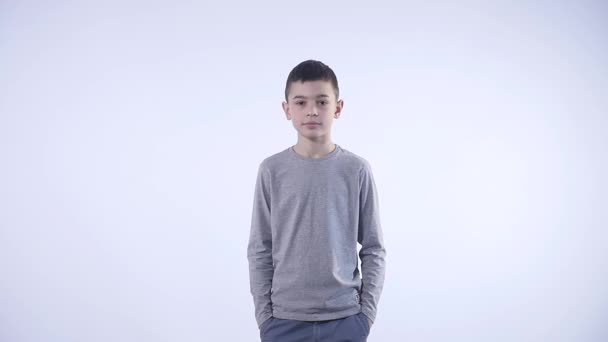 Мальчик подмигивает в камеру на белом фоне — стоковое видео