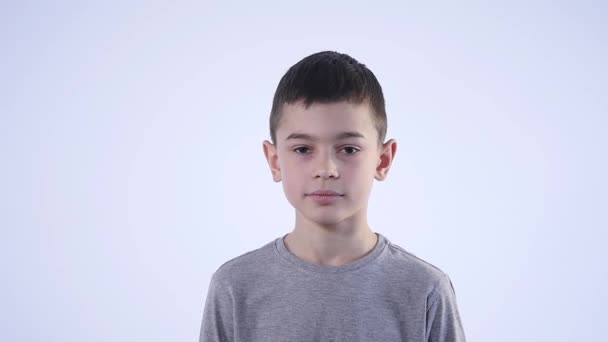 Young boy winking at camera on white background — Stock Video