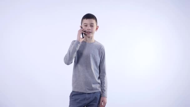 Kleine jongen met een telefoontje geïsoleerd op witte achtergrond — Stockvideo