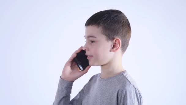 Niño pequeño teniendo una llamada telefónica aislada sobre fondo blanco — Vídeo de stock