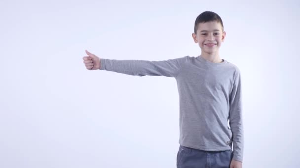 Sorrindo menino segurando seu polegar isolado no fundo branco — Vídeo de Stock