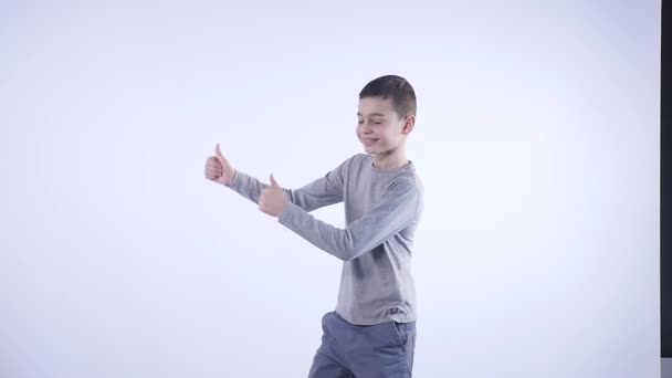 Улыбающийся мальчик, держащий большой палец на белом фоне — стоковое видео