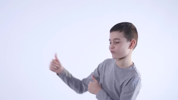 Sorrindo menino segurando seu polegar isolado no fundo branco — Vídeo de Stock