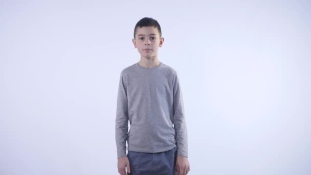 Χαριτωμένο μικρό αγόρι κάνει αστεία πρόσωπα σε λευκό φόντο — Αρχείο Βίντεο
